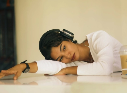 Mujer recostada sobre una mesa con audífonos, en actitud de cansancio y reflexión, que acompaña una nota sobre el proceso emocional de independizarse.