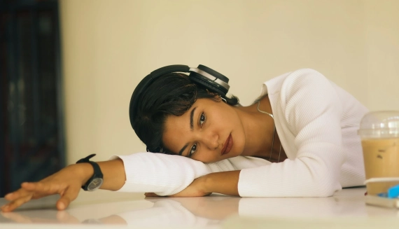 Mujer recostada sobre una mesa con audífonos, en actitud de cansancio y reflexión, que acompaña una nota sobre el proceso emocional de independizarse.