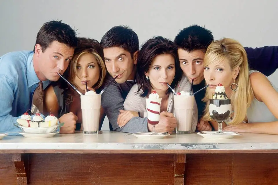 Personajes de Friends compartiendo malteadas en una cafetería, serie clásica de confort sobre amistad y vida adulta